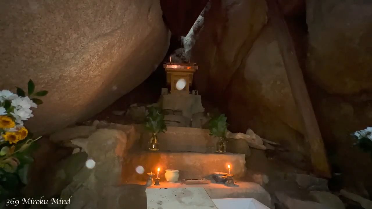 巨岩の間に祀られた祠と、灯明がともる祭壇