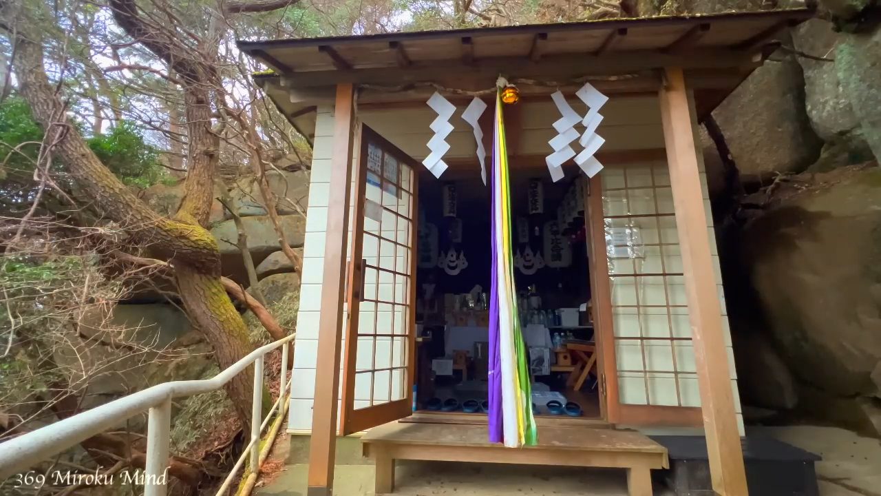 紙垂と五色の布が下がる六甲比命大善神社の社殿。背後に大きな岩が迫る